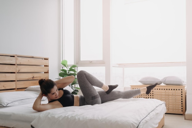 Woman do cross body crunch exercise in her bedroom apartment