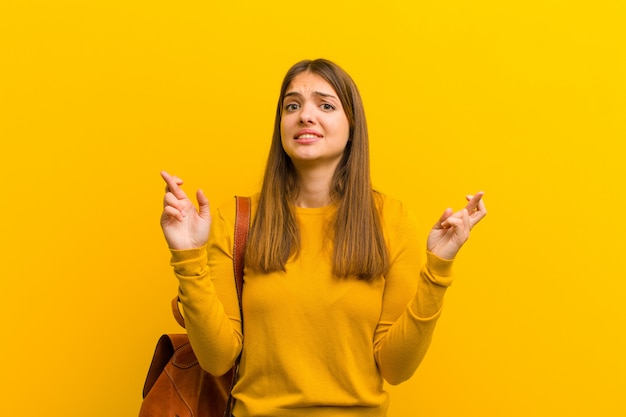 woman crossing fingers anxiously and hoping for good luck with a worried look