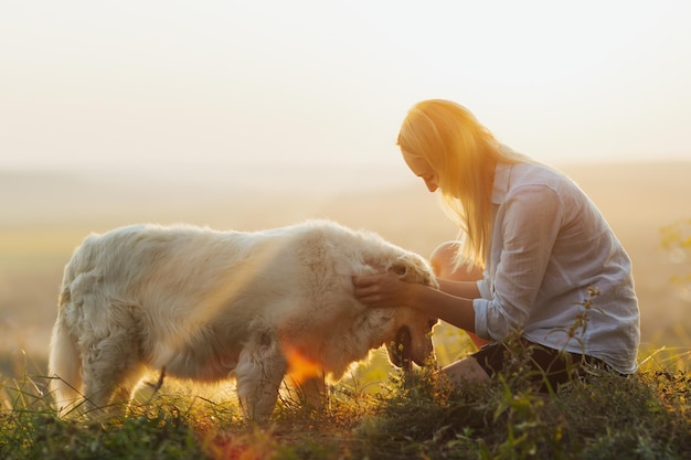 woman cuddling with cute white dog in summer meadow