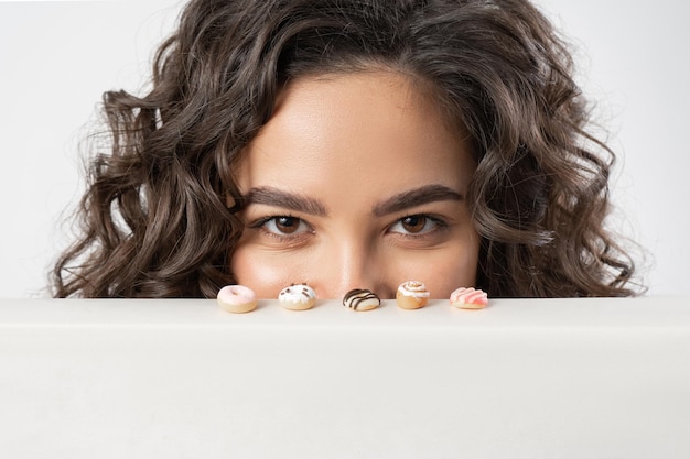 A woman cunningly and intriguingly looks at miniature donuts wanting to eat them