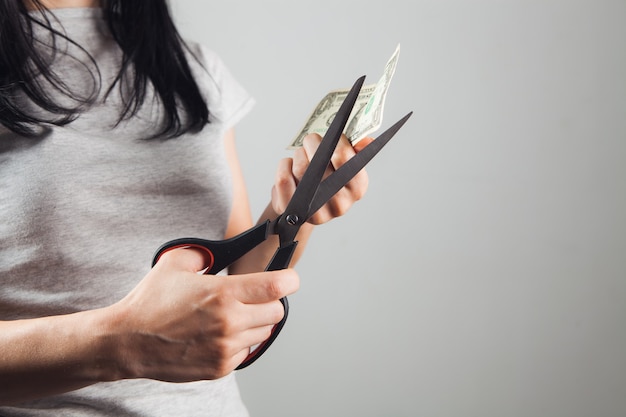 Woman cuts a dollar bill with scissors