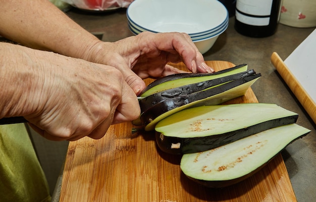 Woman cuts eggplants for cooking at home using recipe from the Internet