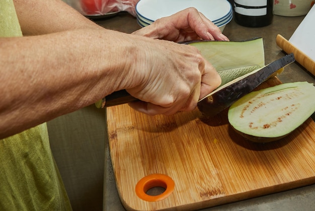 Woman cuts eggplants for cooking at home using recipe from the Internet