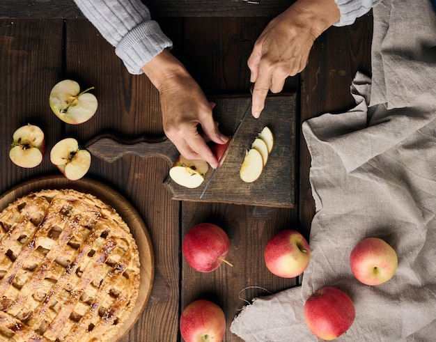 Woman cutting apples for pie on brown wooden table top view