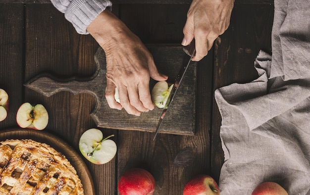 Woman cutting apples for pie on brown wooden table