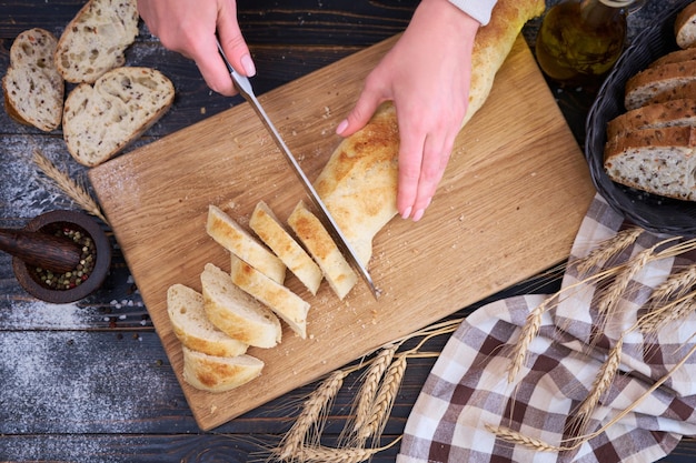 Woman cutting freshly baked bread at wooden kitchen table