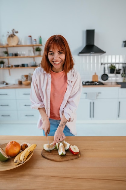 Woman cutting fruits on a board while making breakfast