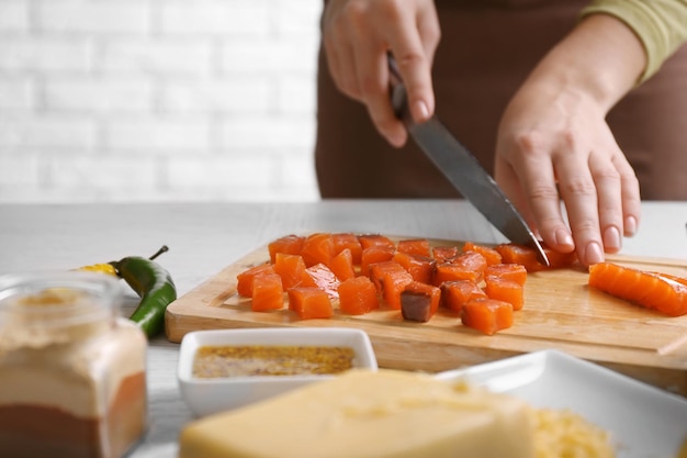 Woman cutting smoked salmon for salad at kitchen