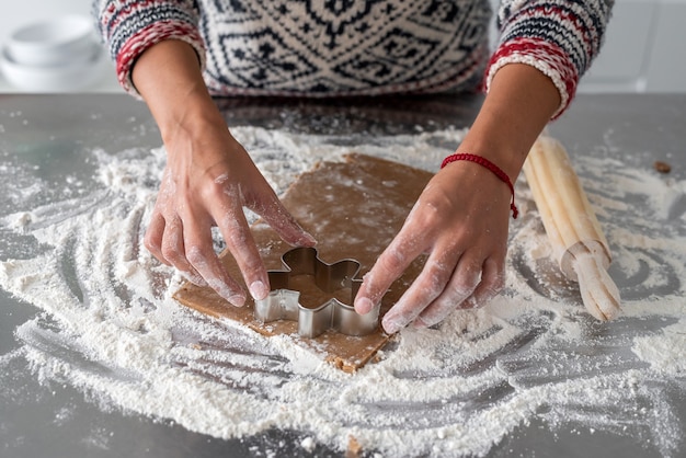 Woman cutting some gingerbread dough with metal cookie cutter man