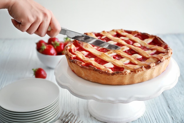 Woman cutting strawberry cake on table