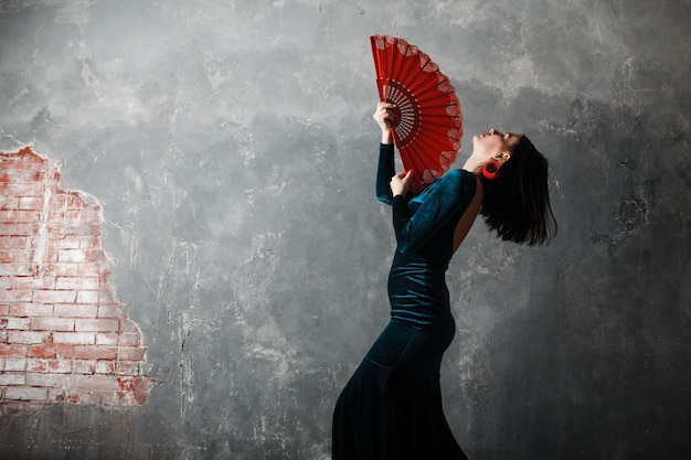 Woman dancer dancing flamenco on gray vintage studio background