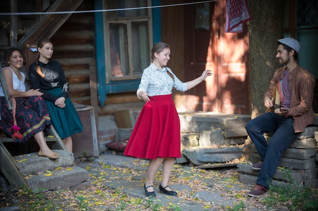 Photo a woman dancing by the music near the country house a man playing balalaika