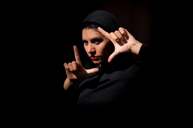 Woman in the dark deep gaze between her hands black background