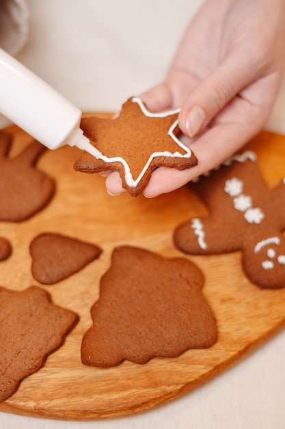 Woman decorates a traditional gingerbread star for the christmas and new year holidays closeup view