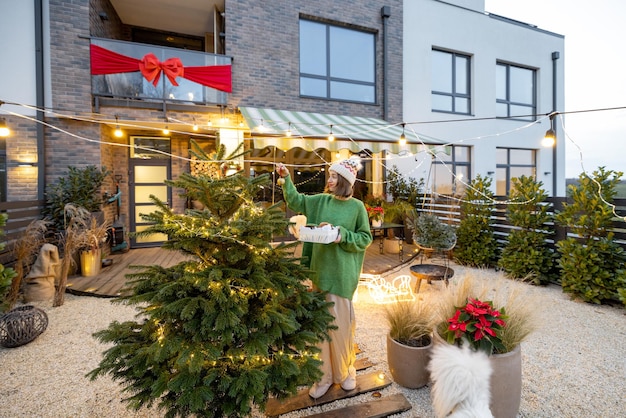 Woman decorating christmas tree at backyard