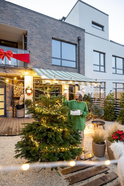 Woman decorating christmas tree at backyard