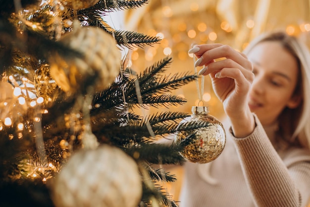 Woman decorating Christmas tree with toys