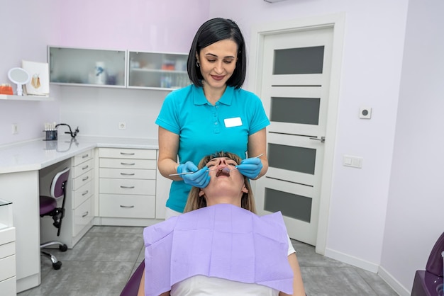 A woman dentist and her assistant in examine the teeth of a woman who came to the reception