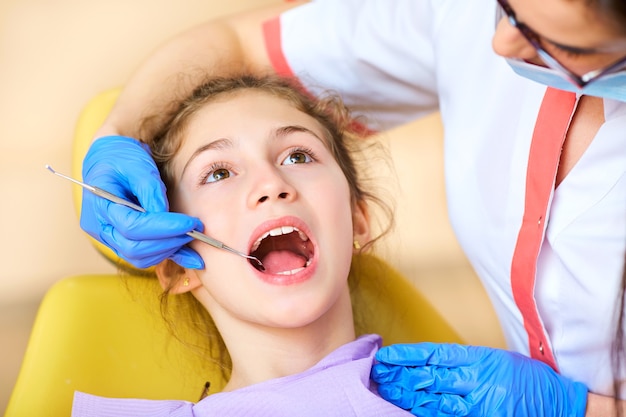 Woman dentist treats your child's teeth in the dental office.