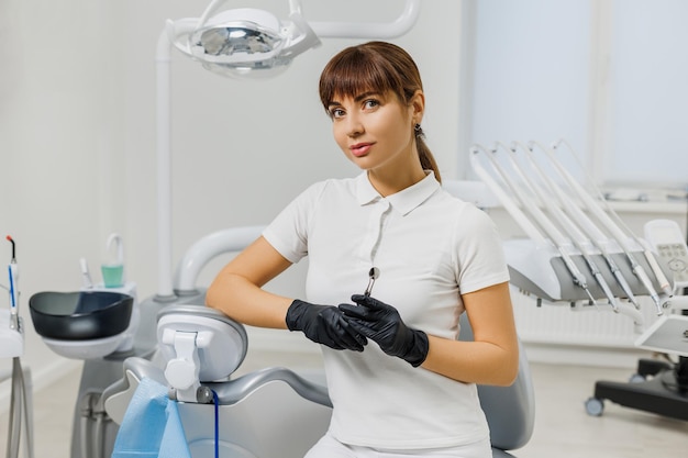 Woman dentist in white uniform and gloves sitting in stomatology cabinet