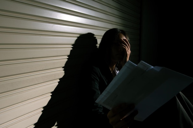 Woman depressed from sad stress pain despair problem person sit on closed shop on corridor alone with emotion lonely desperate upset head down Head in hand no way out concept copy space