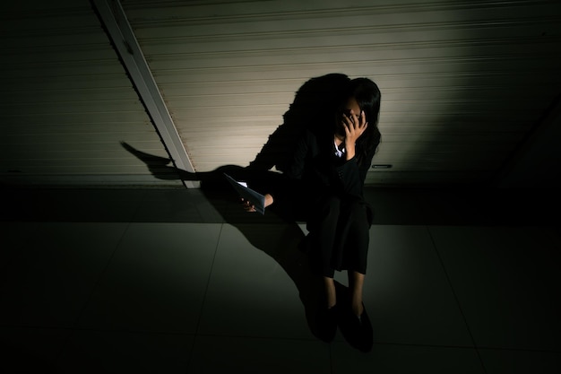 Woman depressed from sad stress pain despair problem person sit on closed shop on corridor alone with emotion lonely desperate upset head down Head in hand no way out concept copy space