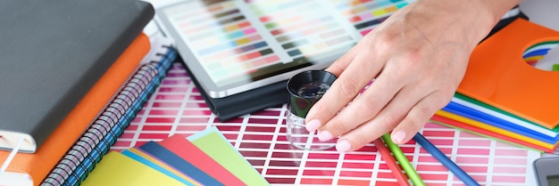 Woman designer looks through magnifying glass at color palette with different shades of colors