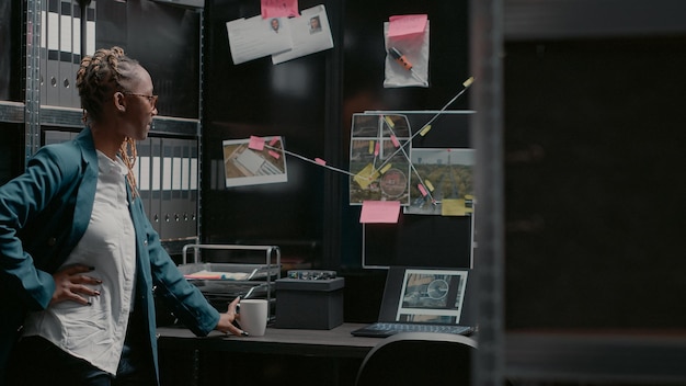 Photo woman detective analyzing evidence from forensics, looking at map with photos and case clues to solve crime. private inspector examining security information in law agency office.