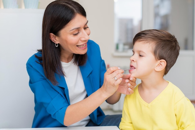 A woman develops a tongue for a boy with a speech therapy probe