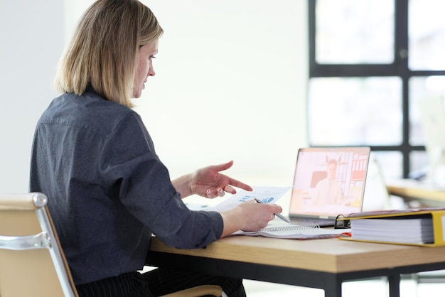 Woman discusses statistic data with colleague on video call via laptop female manager shows