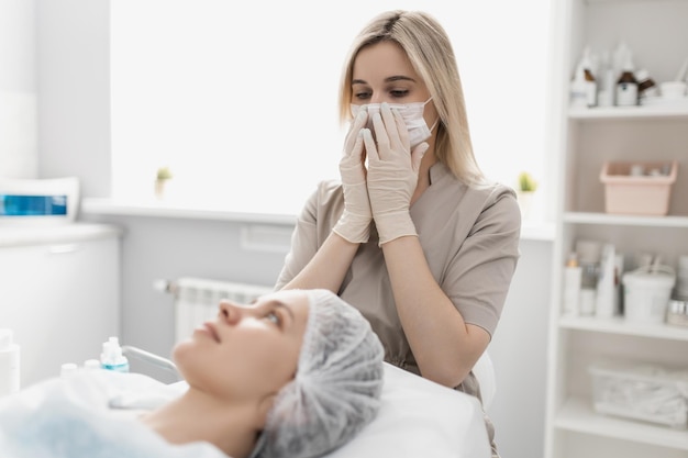 Woman doctor cosmetologist puts a mask on her face before starting procedures