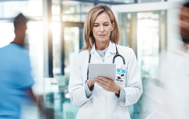 Woman doctor digital tablet planning and healthcare working in busy hospital on medical research online test results and technology Mature focus and expert telehealth surgeon connect clinic app