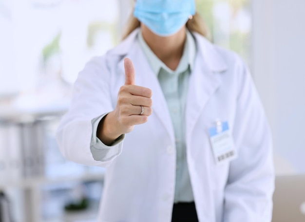 Woman doctor and hands in thumbs up for good job success or winning with mask at the hospital Hand of female medical professional showing thumb emoji yes sign or like for life insurance at clinic