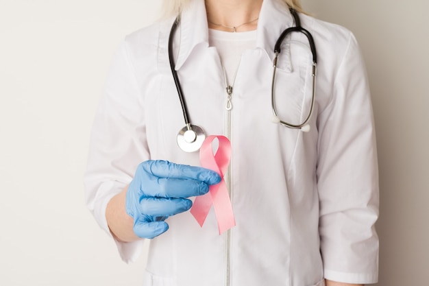 Woman doctor holding a pink ribbon in her hands 