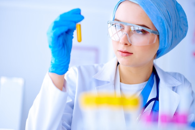 Woman doctor holding test tube Researcher is surrounded by medical vials and flasks