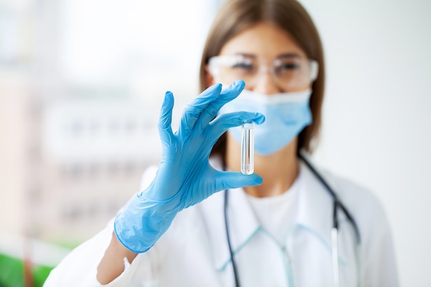 Woman doctor holding test tube with covid-19 coronavirus vaccine.