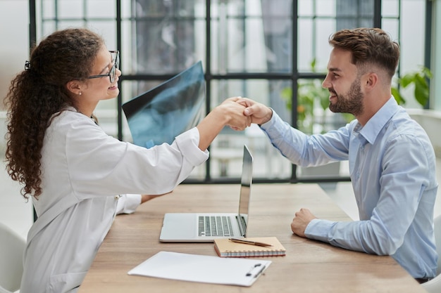 Woman doctor holding an xray in her hands shakes hands with a patient