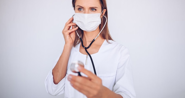 Woman doctor nurse wearing protective mask and stethoscope for check breathing, corona virus prevention, hygiene to stop spreading coronavirus. Avoid contaminating Corona virus Covid-19 concept