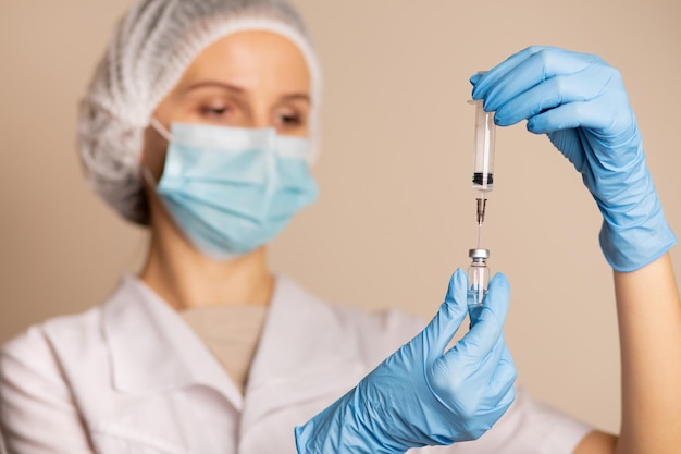 Woman doctor in protective gloves holding syringe with covid 19 vaccine