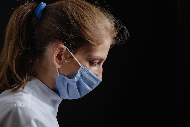 A woman doctor in a protective mask is upset or crying a nurse in a mask is depressed against a blac