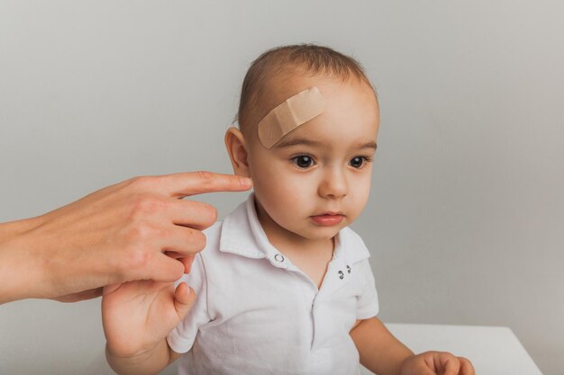 A woman doctor puts a plaster on the boy's forehead indoors. studio photo. health concept