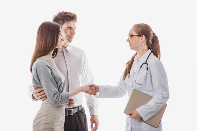 Woman doctor shaking hands with couple