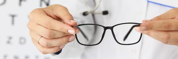 Woman doctors hands hold new stylish glasses in optics closeup selection of glasses for working