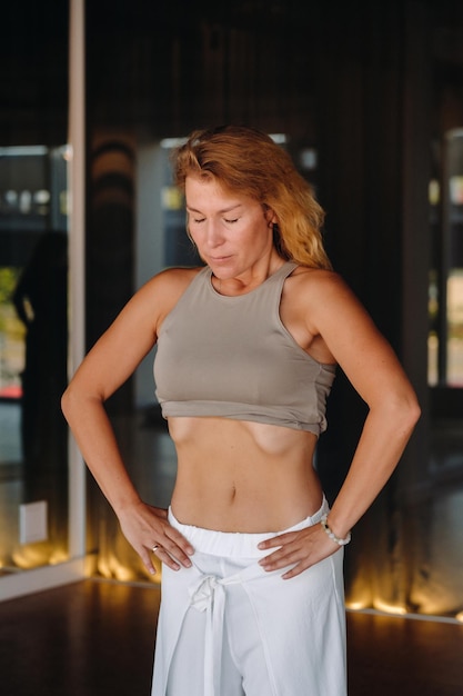 A woman does breathing exercises in the fitness room Home sports training for the muscles of the press