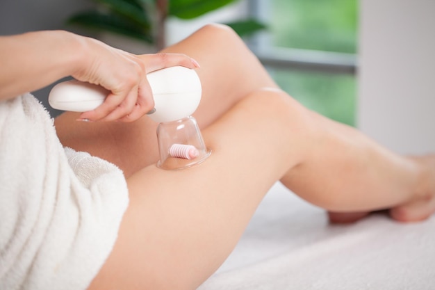 A woman does a hip massage with a vacuum jar for an anticellulite massage