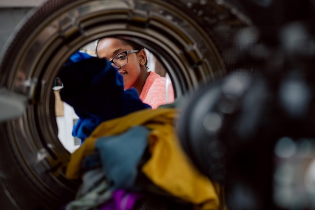 Woman does laundry reaches inside washing machine takes out colored clothes after spinning