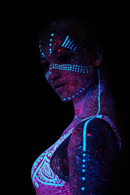 Woman does yoga, hand movement, body warm-up. Art girl cosmos in ultraviolet light. Entire body is covered with colored droplets