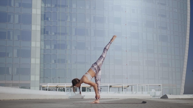 Woman doing downward facing dog pose Girl performing yoga exercises on street