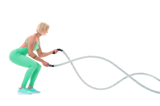 Woman doing exercises with battle rope on white