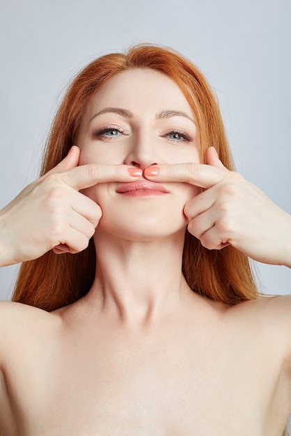 Photo woman doing facial massage, gymnastics, massage lines and plastic mouth eyes and nose. massage technique against wrinkles and skin rejuvenation. russia, sverdlovsk, 12 apr 2019